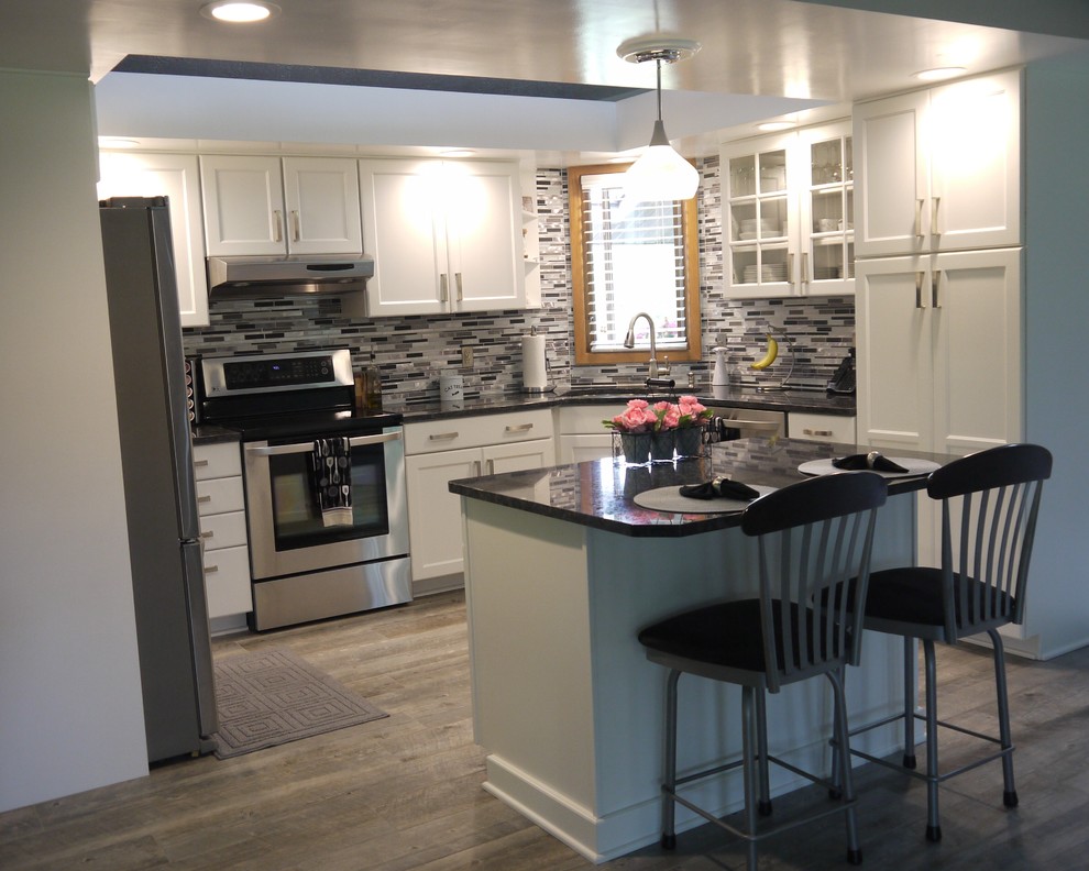 Design ideas for a small transitional u-shaped kitchen in Grand Rapids with a double-bowl sink, recessed-panel cabinets, white cabinets, granite benchtops, multi-coloured splashback, glass tile splashback, stainless steel appliances and with island.
