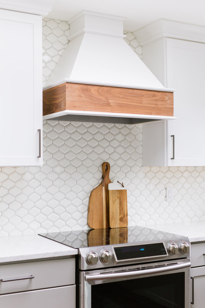 Inspiration for a mid-sized transitional u-shaped medium tone wood floor and brown floor open concept kitchen remodel with an undermount sink, shaker cabinets, white cabinets, quartz countertops, white backsplash, porcelain backsplash, stainless steel appliances, an island and white countertops