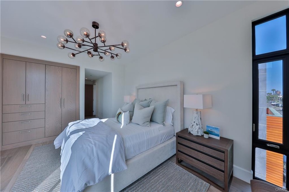 Design ideas for a mid-sized contemporary master bedroom in Los Angeles with white walls, light hardwood floors, no fireplace and brown floor.
