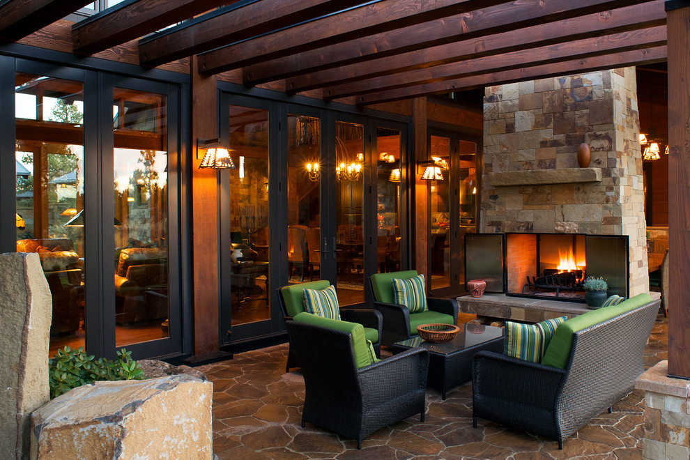Photo of a country patio in Other with natural stone pavers, a fire feature and a pergola.