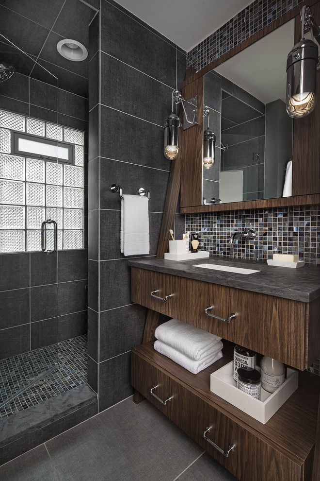 Photo of a small contemporary 3/4 bathroom in Detroit with flat-panel cabinets, medium wood cabinets, an alcove shower, a wall-mount toilet, blue tile, porcelain tile, blue walls, porcelain floors, an undermount sink, granite benchtops, blue floor, a hinged shower door and black benchtops.