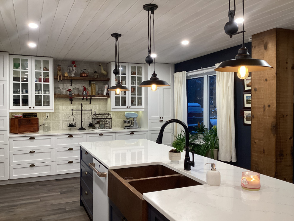 Photo of a large country u-shaped eat-in kitchen in Ottawa with an undermount sink, shaker cabinets, white cabinets, quartzite benchtops, white splashback, ceramic splashback, white appliances, porcelain floors, with island, brown floor, white benchtop and timber.