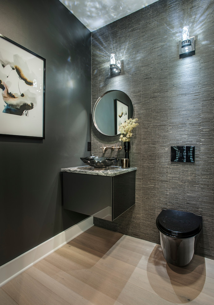 Mid-sized contemporary powder room in Philadelphia with flat-panel cabinets, black cabinets, a wall-mount toilet, grey walls, light hardwood floors, a vessel sink and beige floor.