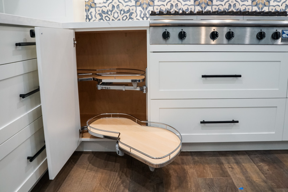 Inspiration for a mid-sized midcentury l-shaped kitchen in Miami with recessed-panel cabinets, white cabinets, quartzite benchtops, mosaic tile splashback, stainless steel appliances, porcelain floors, with island, brown floor and white benchtop.