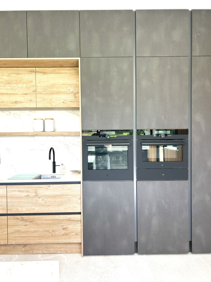 Diseño de cocina contemporánea grande con armarios con paneles lisos, electrodomésticos negros y una isla