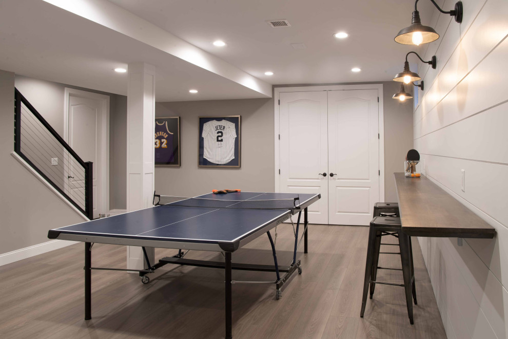 Large transitional medium tone wood floor and brown floor game room photo in New York with gray walls