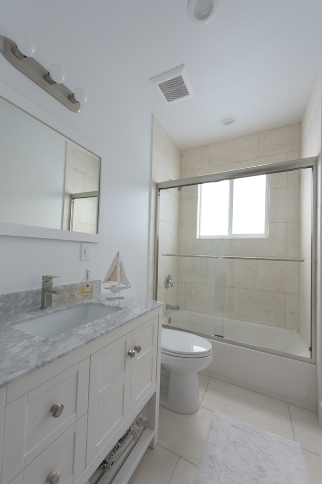 Mid-sized beach style 3/4 bathroom in Miami with shaker cabinets, white cabinets, an alcove tub, a shower/bathtub combo, a two-piece toilet, white walls, ceramic floors, an undermount sink and soapstone benchtops.