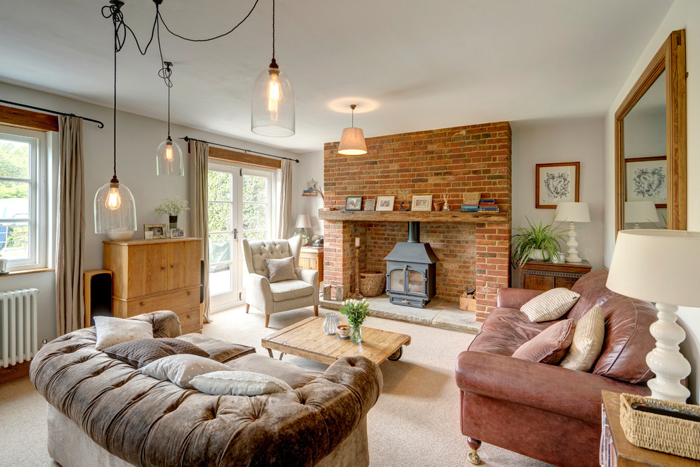 Design ideas for a country enclosed living room in Kent with carpet, a brick fireplace surround, a freestanding tv, beige floor, white walls and a wood stove.