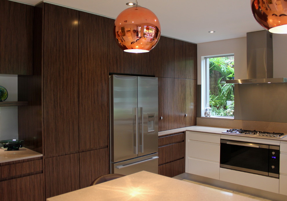 This is an example of a mid-sized contemporary u-shaped kitchen pantry in Sydney with dark wood cabinets, solid surface benchtops, metallic splashback, with island, a drop-in sink, flat-panel cabinets, ceramic splashback, stainless steel appliances and ceramic floors.
