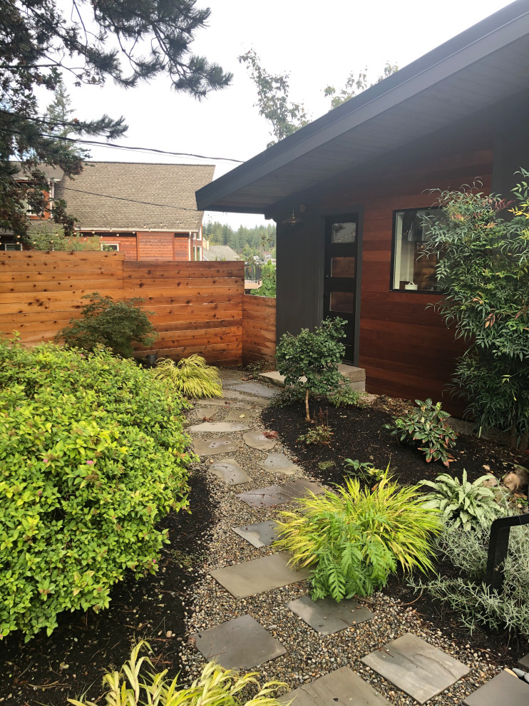 Photo of a large midcentury two-storey black house exterior in Seattle with wood siding, a shed roof, a metal roof and a black roof.