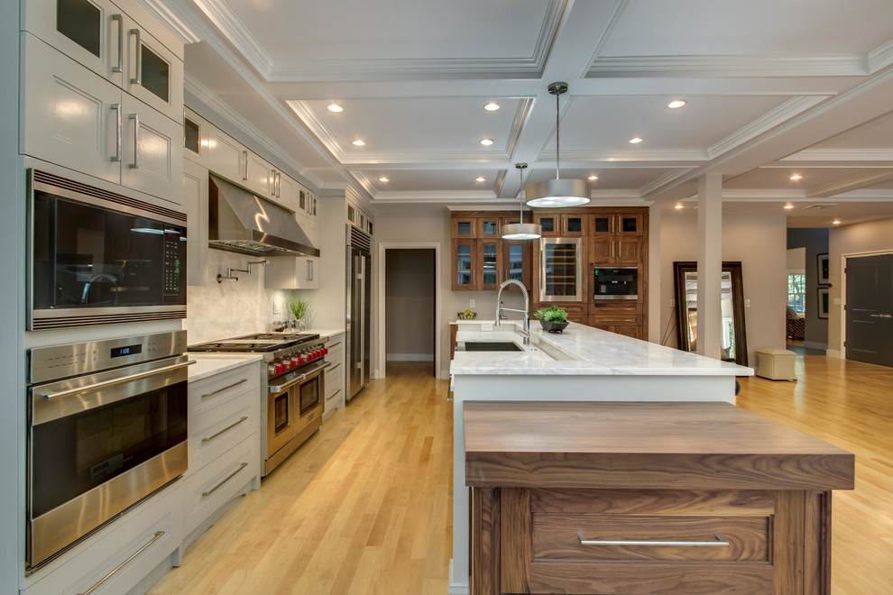 This is an example of a large traditional l-shaped open plan kitchen in Boston with a double-bowl sink, recessed-panel cabinets, grey cabinets, marble benchtops, white splashback, marble splashback, stainless steel appliances, light hardwood floors and with island.