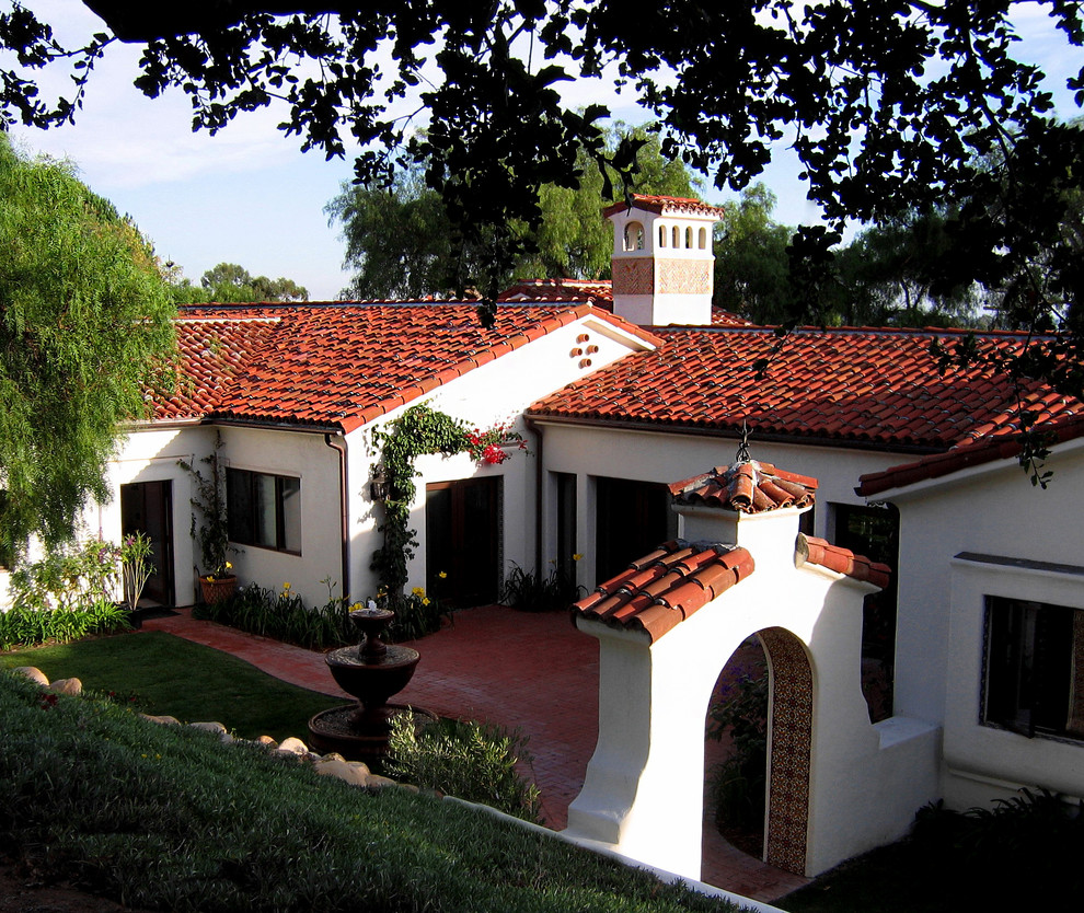 Design ideas for a mid-sized mediterranean one-storey stucco white house exterior in Santa Barbara with a clipped gable roof and a tile roof.