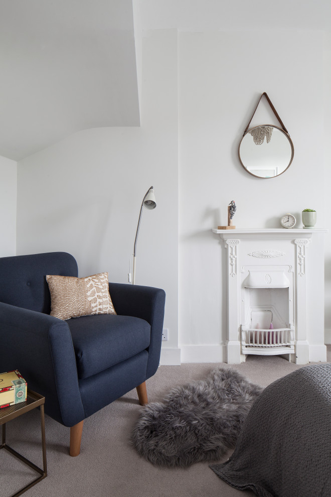 Photo of a mid-sized scandinavian guest bedroom in Sussex with white walls, carpet, a metal fireplace surround and grey floor.