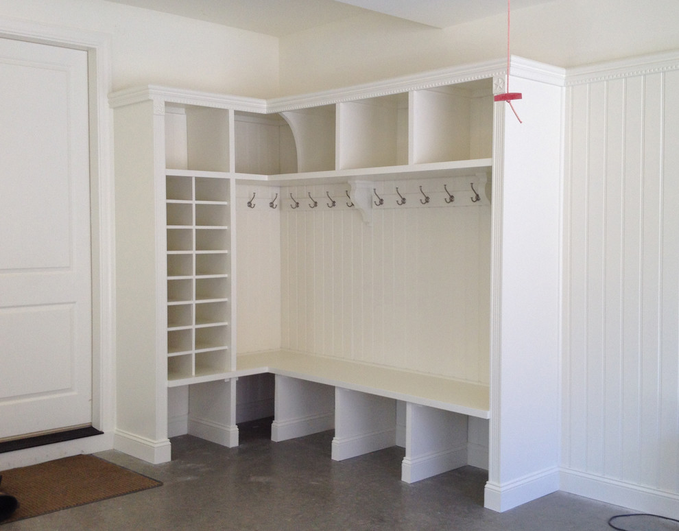 Photo of a mid-sized traditional mudroom in Charlotte with white walls, concrete floors, a single front door and a medium wood front door.