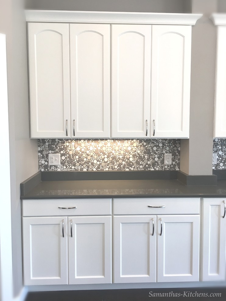Inspiration for a mid-sized transitional l-shaped dark wood floor home design remodel with an undermount sink, recessed-panel cabinets, gray cabinets, quartz countertops, white backsplash, ceramic backsplash, stainless steel appliances and an island