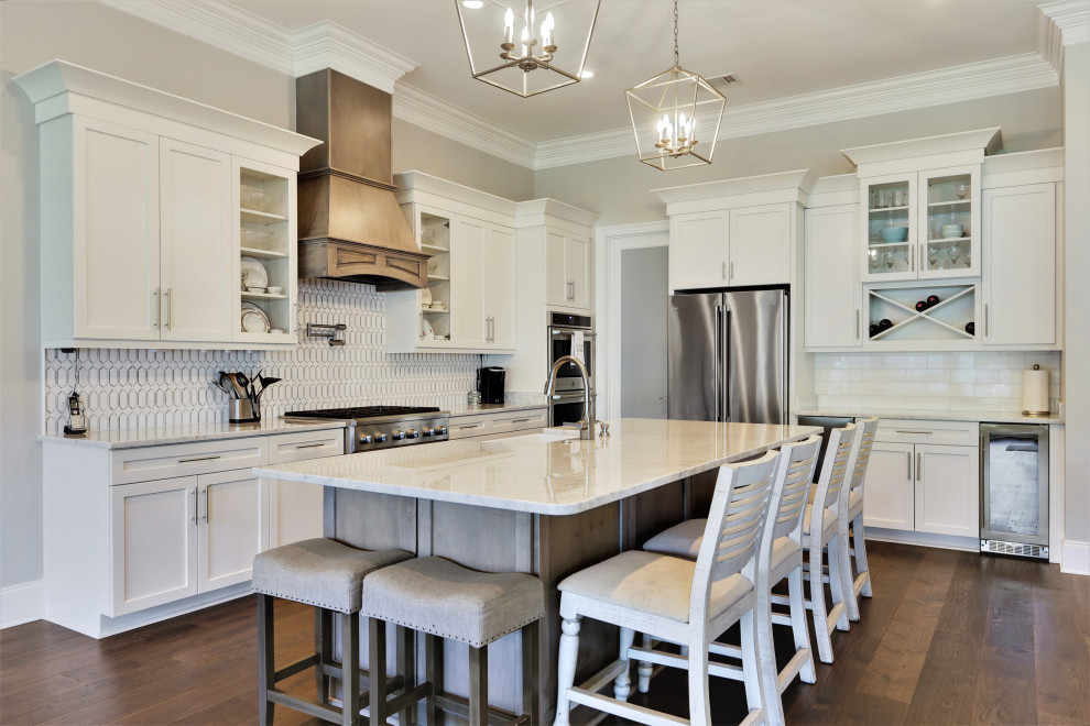 Transitional l-shaped medium tone wood floor and brown floor kitchen photo with a farmhouse sink, shaker cabinets, white cabinets, quartz countertops, white backsplash, subway tile backsplash, stainless steel appliances, an island and white countertops