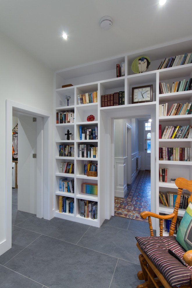 Photo of a mid-sized contemporary home office in London with a library, white walls, terra-cotta floors, no fireplace and multi-coloured floor.