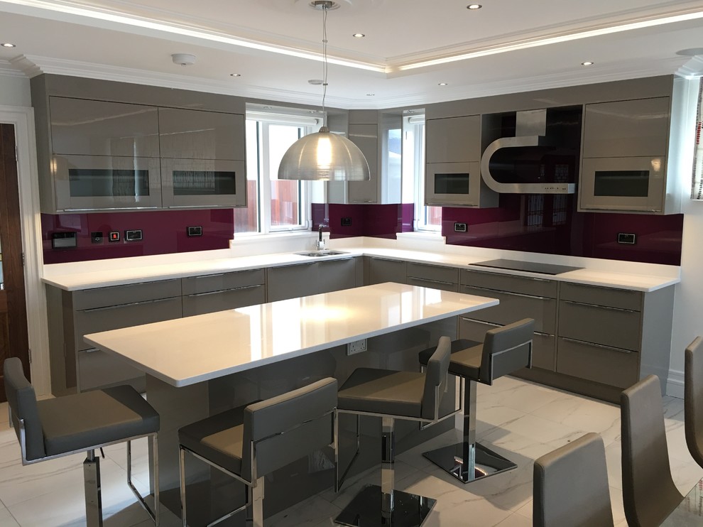 This is an example of a large contemporary l-shaped eat-in kitchen in Dublin with an undermount sink, flat-panel cabinets, grey cabinets, pink splashback, coloured appliances, marble floors and a peninsula.