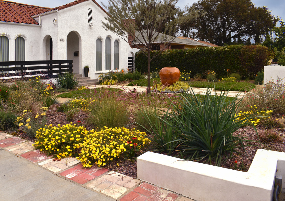 This is an example of a small contemporary front yard full sun xeriscape for spring with a garden path and concrete pavers.