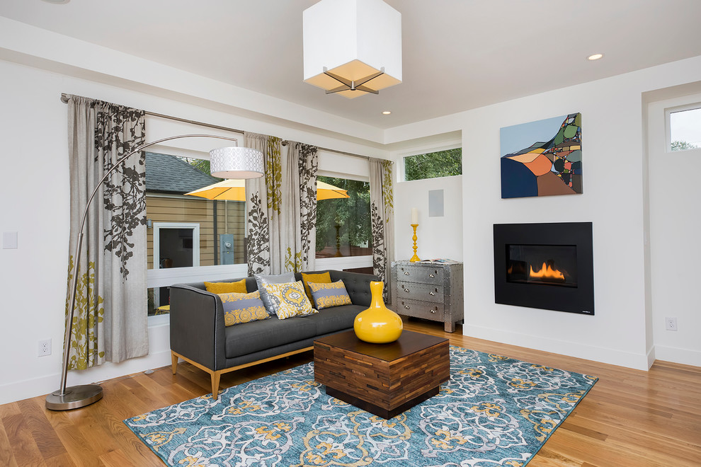 Inspiration for a mid-sized contemporary formal open concept living room in Denver with white walls, light hardwood floors, a standard fireplace, a plaster fireplace surround and a freestanding tv.