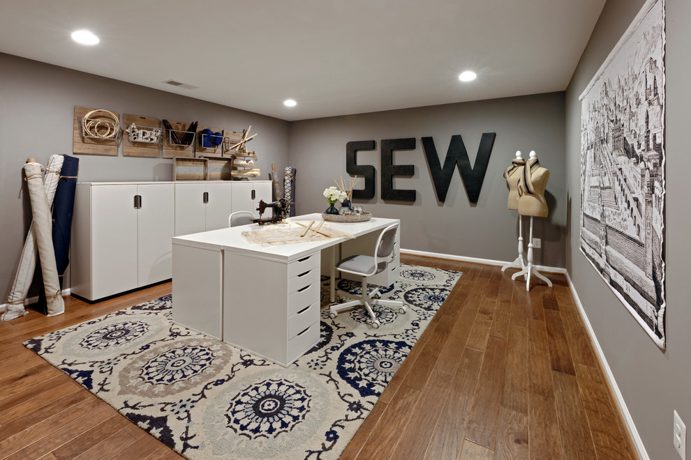 Inspiration for a large transitional craft room in DC Metro with grey walls, vinyl floors, no fireplace, a freestanding desk and brown floor.