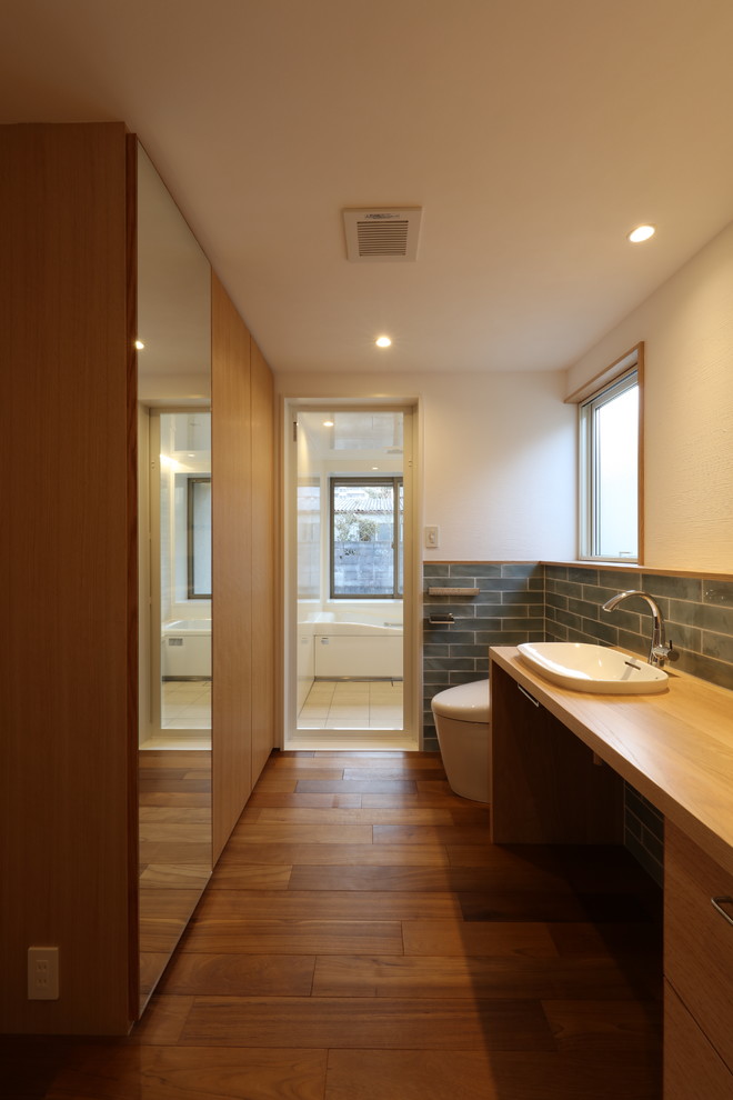 Midcentury powder room in Other with a one-piece toilet, porcelain tile, white walls, dark hardwood floors, a drop-in sink, wood benchtops, brown floor and brown benchtops.