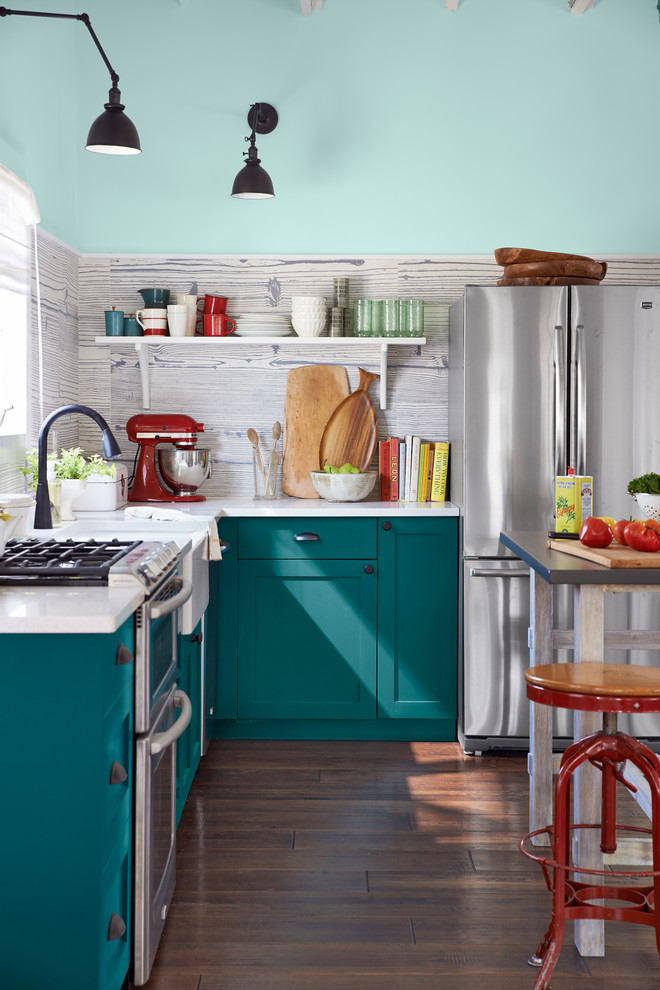 Photo of a small beach style l-shaped kitchen in New York with a farmhouse sink, shaker cabinets, turquoise cabinets, quartz benchtops, grey splashback, porcelain splashback, stainless steel appliances, with island, brown floor, white benchtop and medium hardwood floors.