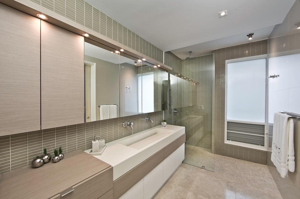 Photo of a mid-sized modern master bathroom in Miami with an integrated sink, flat-panel cabinets, medium wood cabinets, engineered quartz benchtops, an open shower, a two-piece toilet, gray tile, glass tile, grey walls and marble floors.