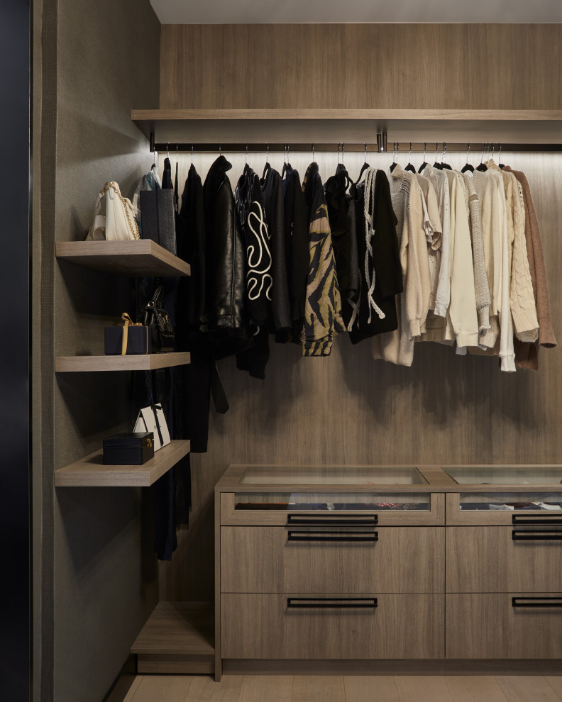 This is an example of a mid-sized contemporary gender-neutral walk-in wardrobe in Toronto with glass-front cabinets, dark wood cabinets, light hardwood floors and beige floor.