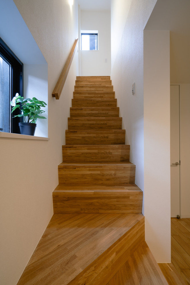 Imagen de escalera recta minimalista con escalones de madera, contrahuellas de madera, barandilla de madera y papel pintado