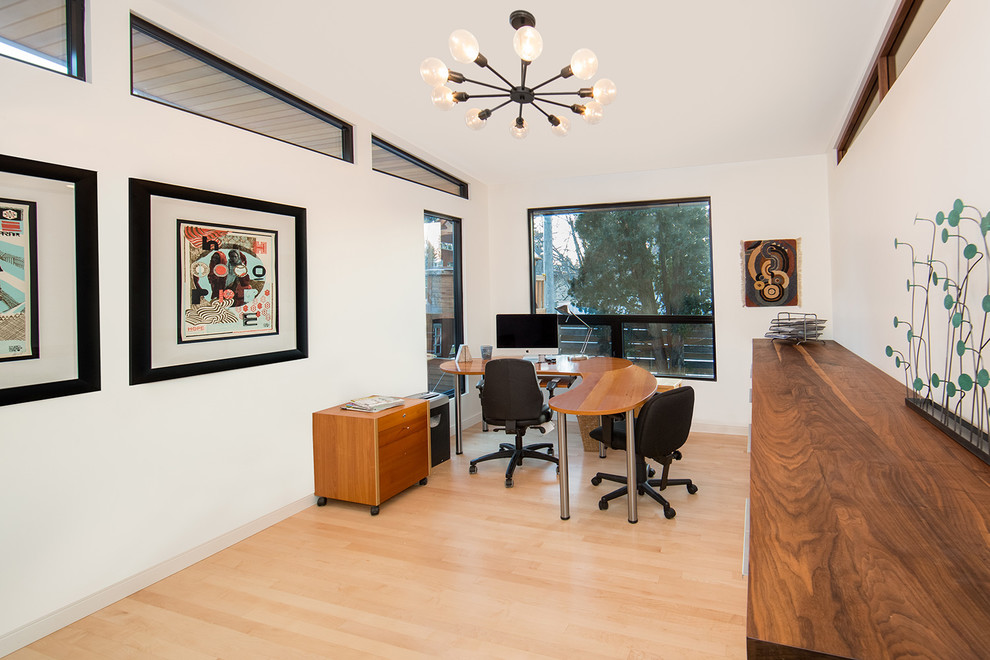 Photo of a mid-sized contemporary study room in Other with white walls, light hardwood floors, no fireplace, a freestanding desk and beige floor.