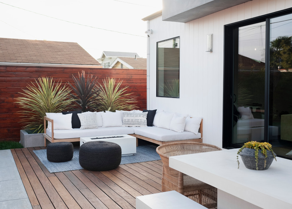 This is an example of a mid-sized beach style backyard deck in Los Angeles with a fire feature and no cover.