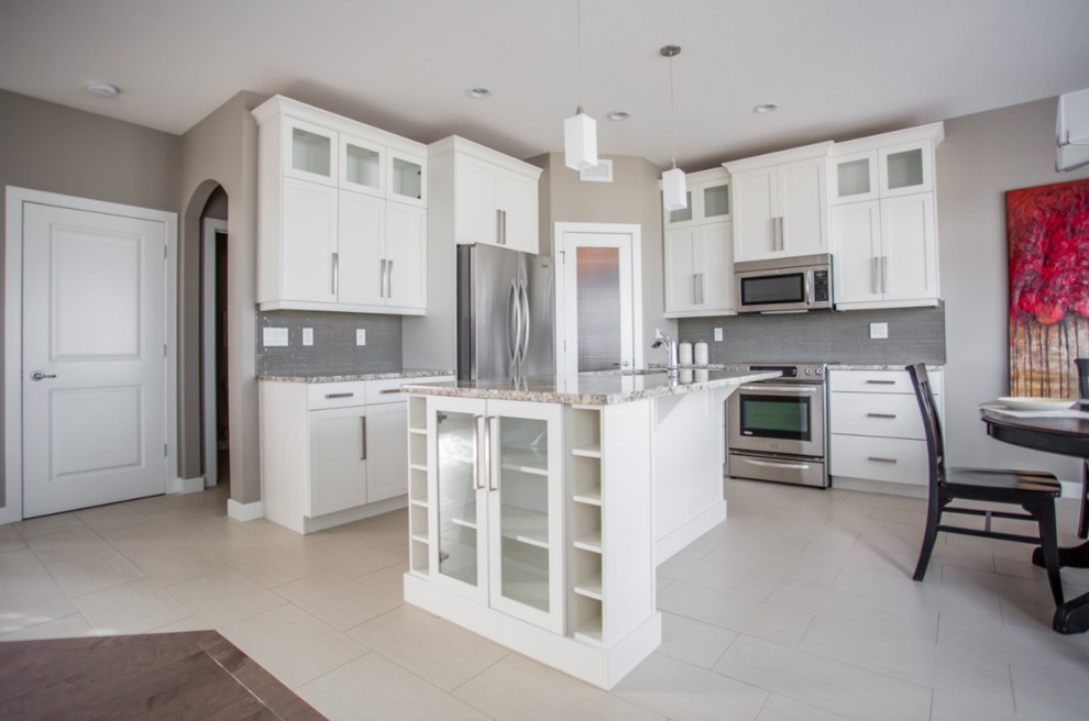 Example of a mid-sized transitional l-shaped vinyl floor open concept kitchen design with an undermount sink, shaker cabinets, white cabinets, granite countertops, gray backsplash, paneled appliances and an island