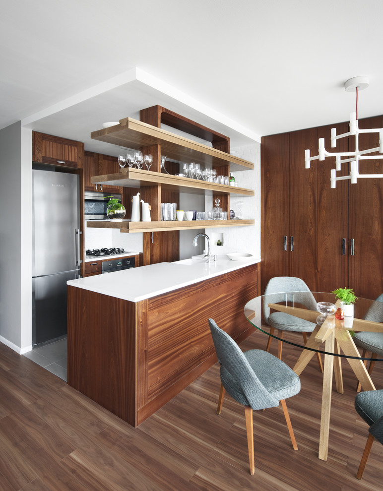 Mid-sized scandinavian galley eat-in kitchen in New York with a farmhouse sink, flat-panel cabinets, dark wood cabinets, solid surface benchtops, stainless steel appliances, porcelain floors and no island.
