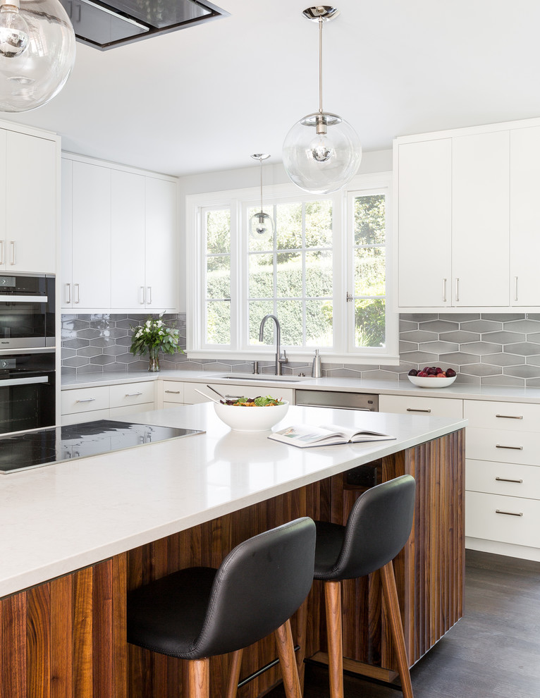 Contemporary l-shaped kitchen in Portland with an undermount sink, white cabinets, quartz benchtops, grey splashback, ceramic splashback, stainless steel appliances, dark hardwood floors, with island, brown floor and flat-panel cabinets.