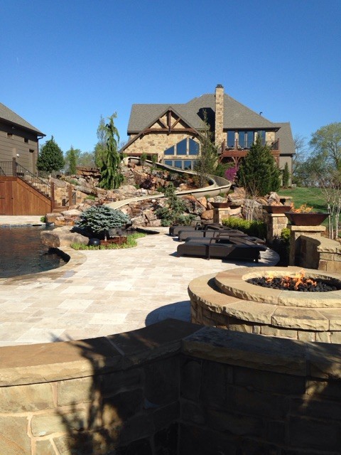 Design ideas for a large country backyard custom-shaped natural pool in Wichita with a hot tub and natural stone pavers.