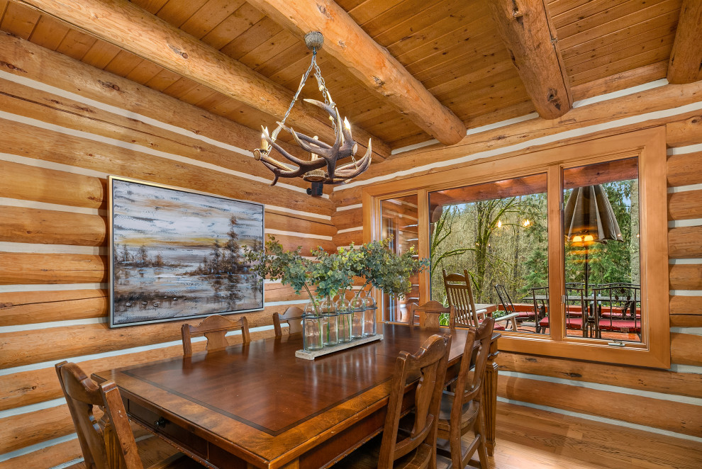 Cette image montre une grande salle à manger chalet en bois fermée avec un sol en bois brun et un plafond en bois.