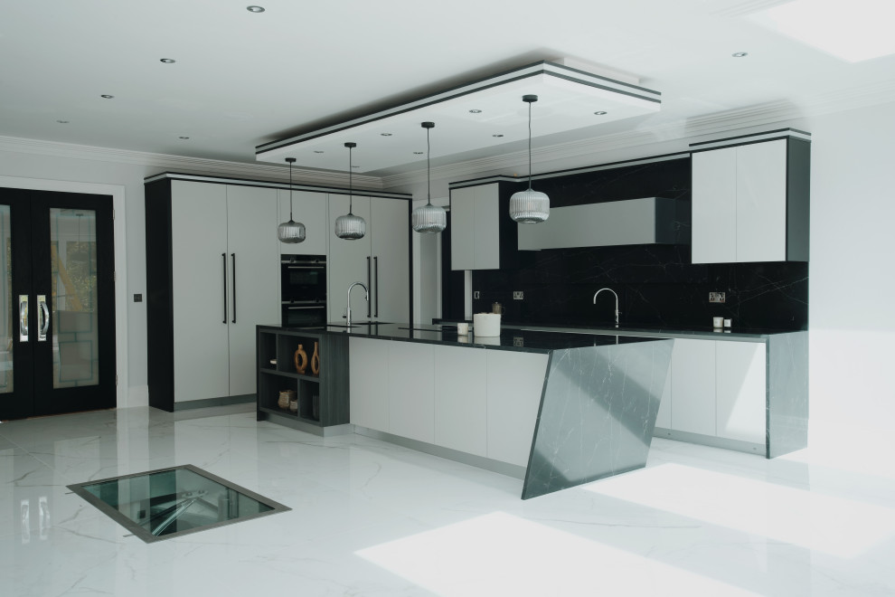 This is an example of a large modern grey and black l-shaped kitchen/diner in Surrey with a built-in sink, flat-panel cabinets, grey cabinets, composite countertops, black splashback, engineered quartz splashback, black appliances, porcelain flooring, an island, white floors, black worktops, a coffered ceiling and feature lighting.