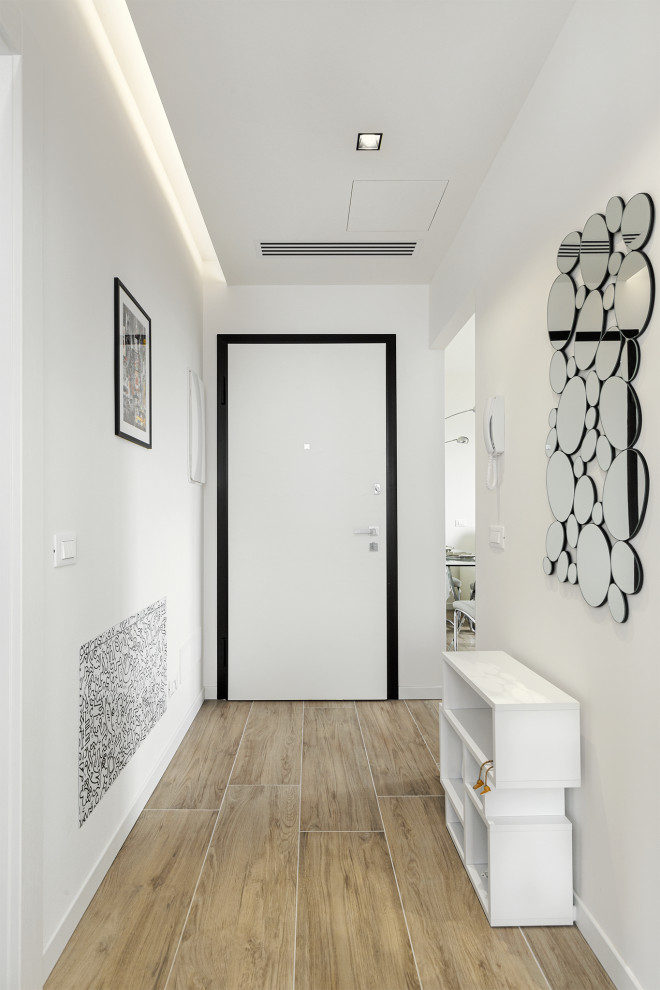 Esempio di un corridoio contemporaneo di medie dimensioni con pareti bianche, pavimento in gres porcellanato, una porta singola, una porta bianca, pavimento marrone, soffitto ribassato e pannellatura