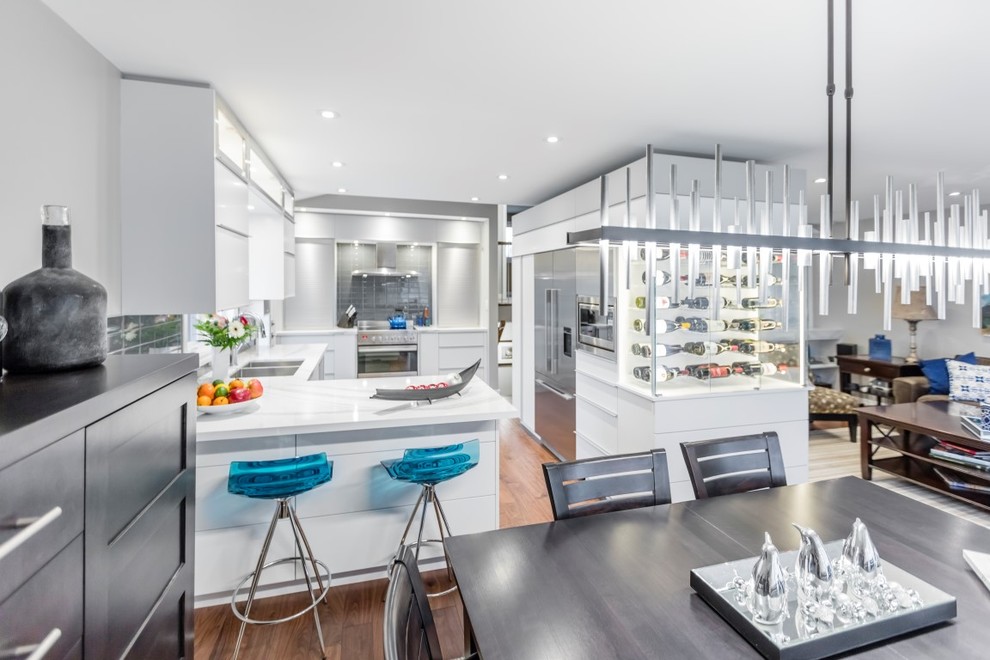 Inspiration for a mid-sized contemporary u-shaped eat-in kitchen in Orange County with a double-bowl sink, flat-panel cabinets, white cabinets, solid surface benchtops, stainless steel appliances, medium hardwood floors and a peninsula.