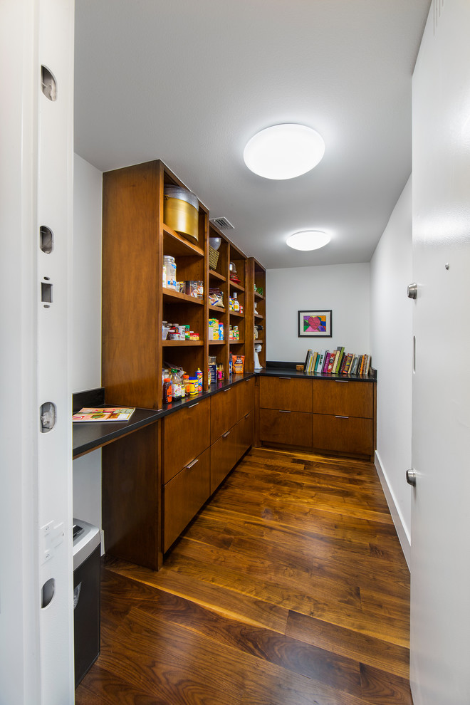 Photo of a mid-sized midcentury gender-neutral walk-in wardrobe in Dallas with flat-panel cabinets, medium wood cabinets, medium hardwood floors and brown floor.