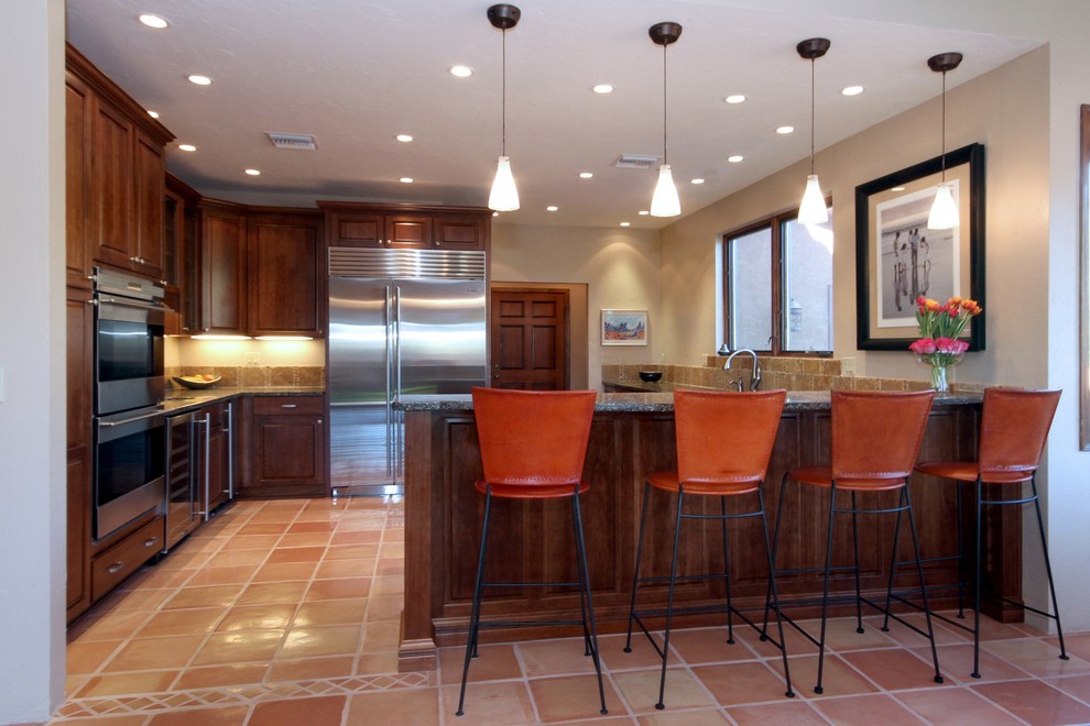Large transitional u-shaped terra-cotta tile eat-in kitchen photo in Phoenix with an undermount sink, raised-panel cabinets, medium tone wood cabinets, recycled glass countertops, multicolored backsplash, stone tile backsplash, stainless steel appliances and white walls