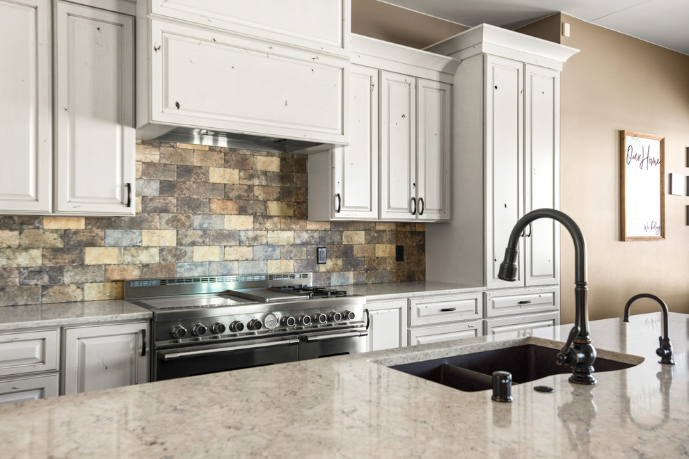 Large transitional l-shaped medium tone wood floor and brown floor eat-in kitchen photo with an undermount sink, raised-panel cabinets, quartz countertops, beige backsplash, stone tile backsplash, stainless steel appliances, an island and beige countertops