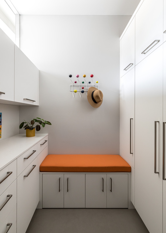 This is an example of a midcentury gender-neutral walk-in wardrobe in Sacramento with flat-panel cabinets, white cabinets, concrete floors and grey floor.