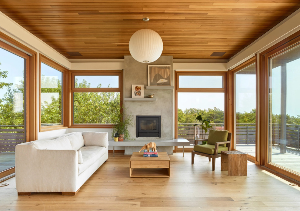 Imagen de salón abierto costero con suelo de madera en tonos medios y madera