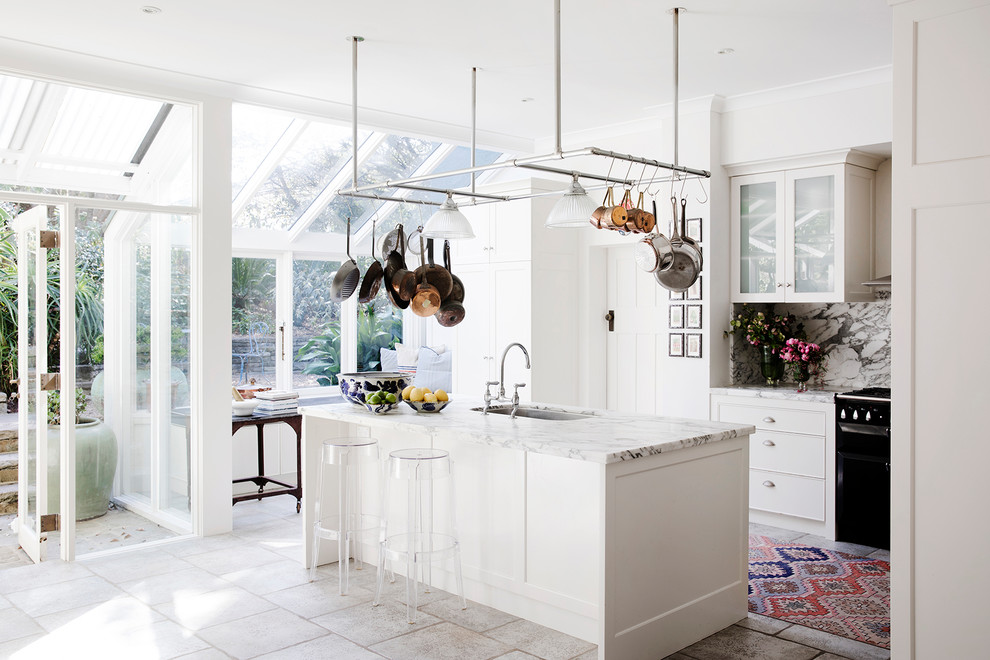 Inspiration for an eclectic u-shaped eat-in kitchen in Sydney with a single-bowl sink, shaker cabinets, white cabinets, grey splashback, black appliances, with island and grey floor.