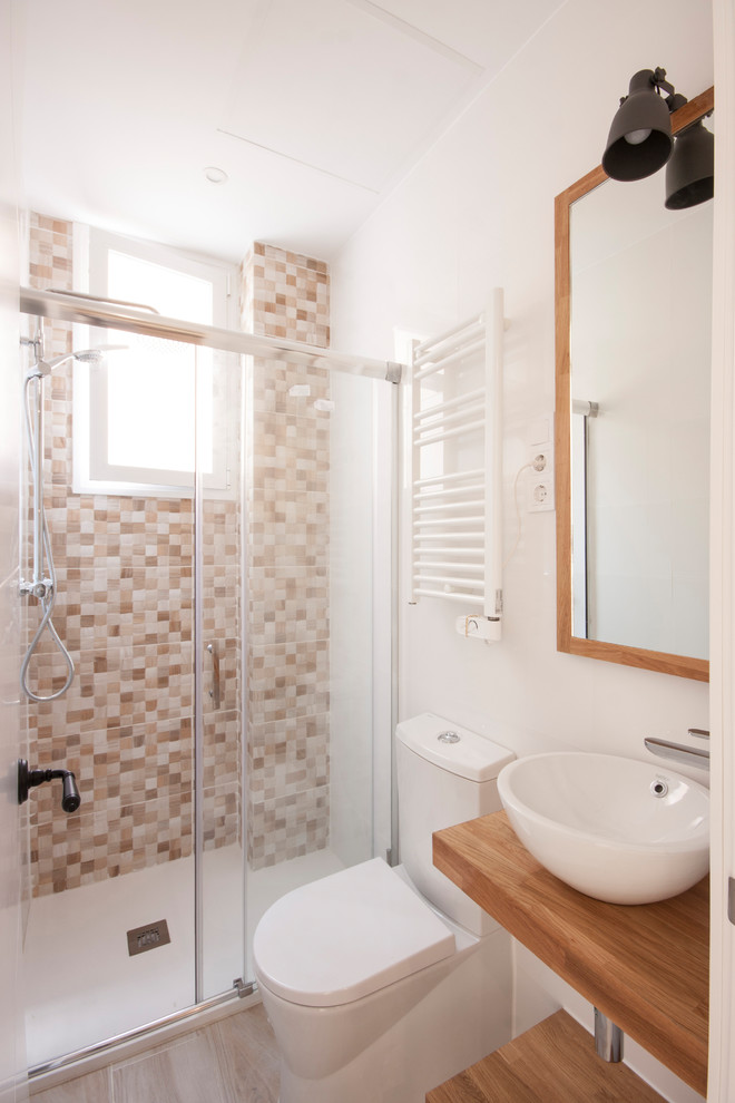 Small contemporary master bathroom in Madrid with a curbless shower, a one-piece toilet, beige tile, ceramic tile, white walls, porcelain floors, a vessel sink, wood benchtops, beige floor and a sliding shower screen.