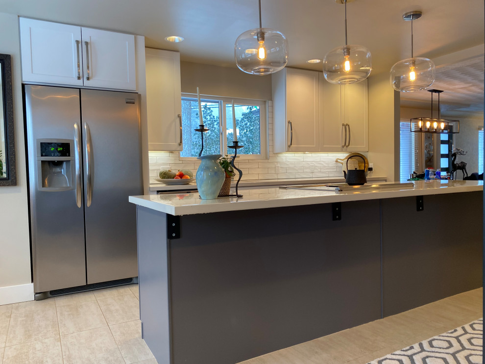 Large contemporary galley kitchen pantry in Seattle with a submerged sink, shaker cabinets, white cabinets, composite countertops, white splashback, metro tiled splashback, stainless steel appliances, porcelain flooring, an island, beige floors and white worktops.