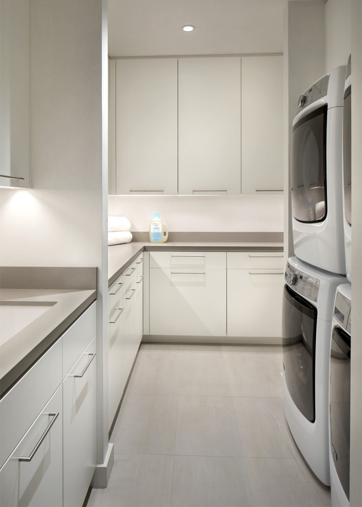 Mid-sized contemporary galley laundry cupboard in Denver with an undermount sink, flat-panel cabinets, medium hardwood floors and a stacked washer and dryer.