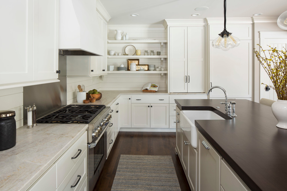 Photo of a country l-shaped kitchen in Minneapolis with a farmhouse sink, shaker cabinets, white cabinets, stainless steel appliances, dark hardwood floors and with island.